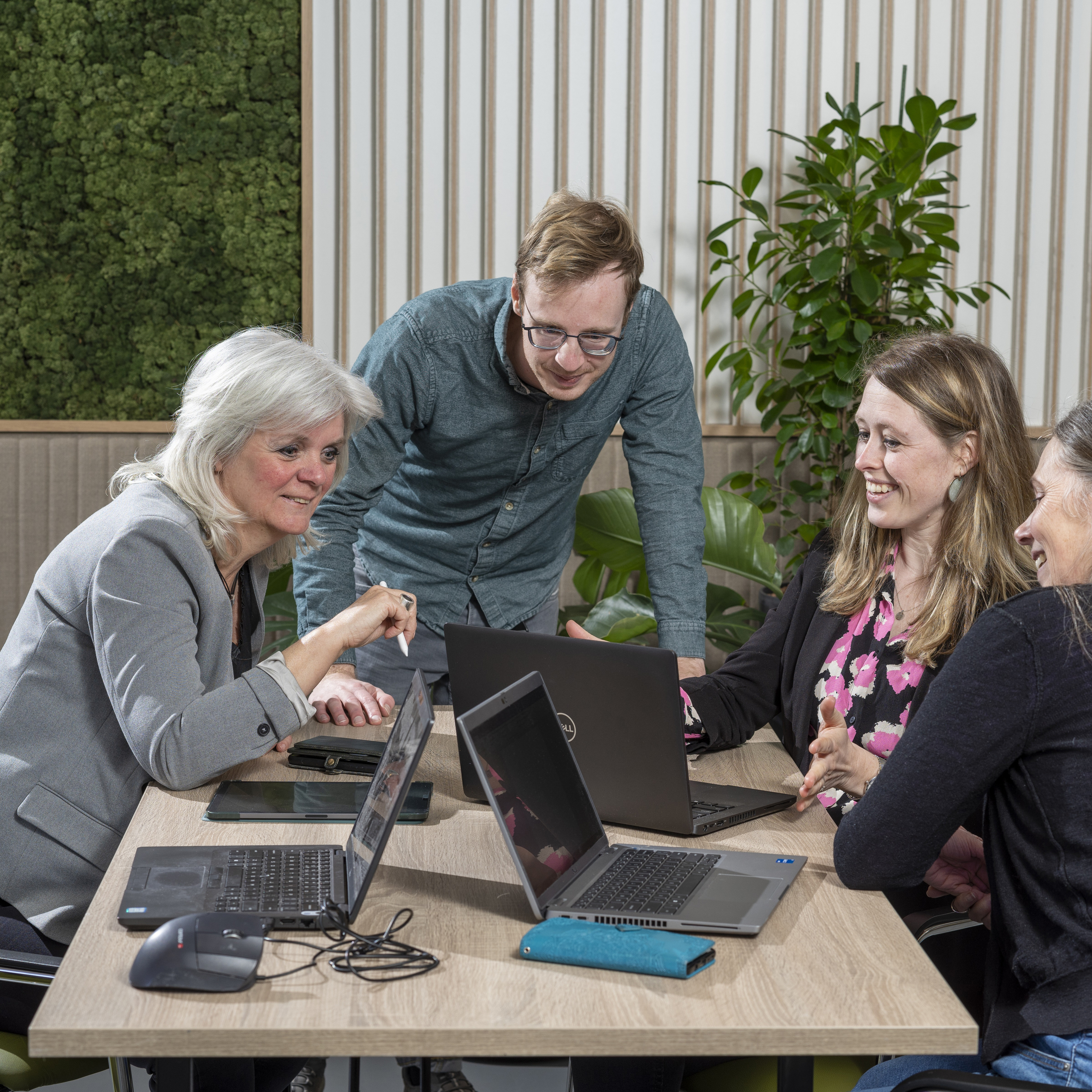 4 collega's rond tafel met laptops